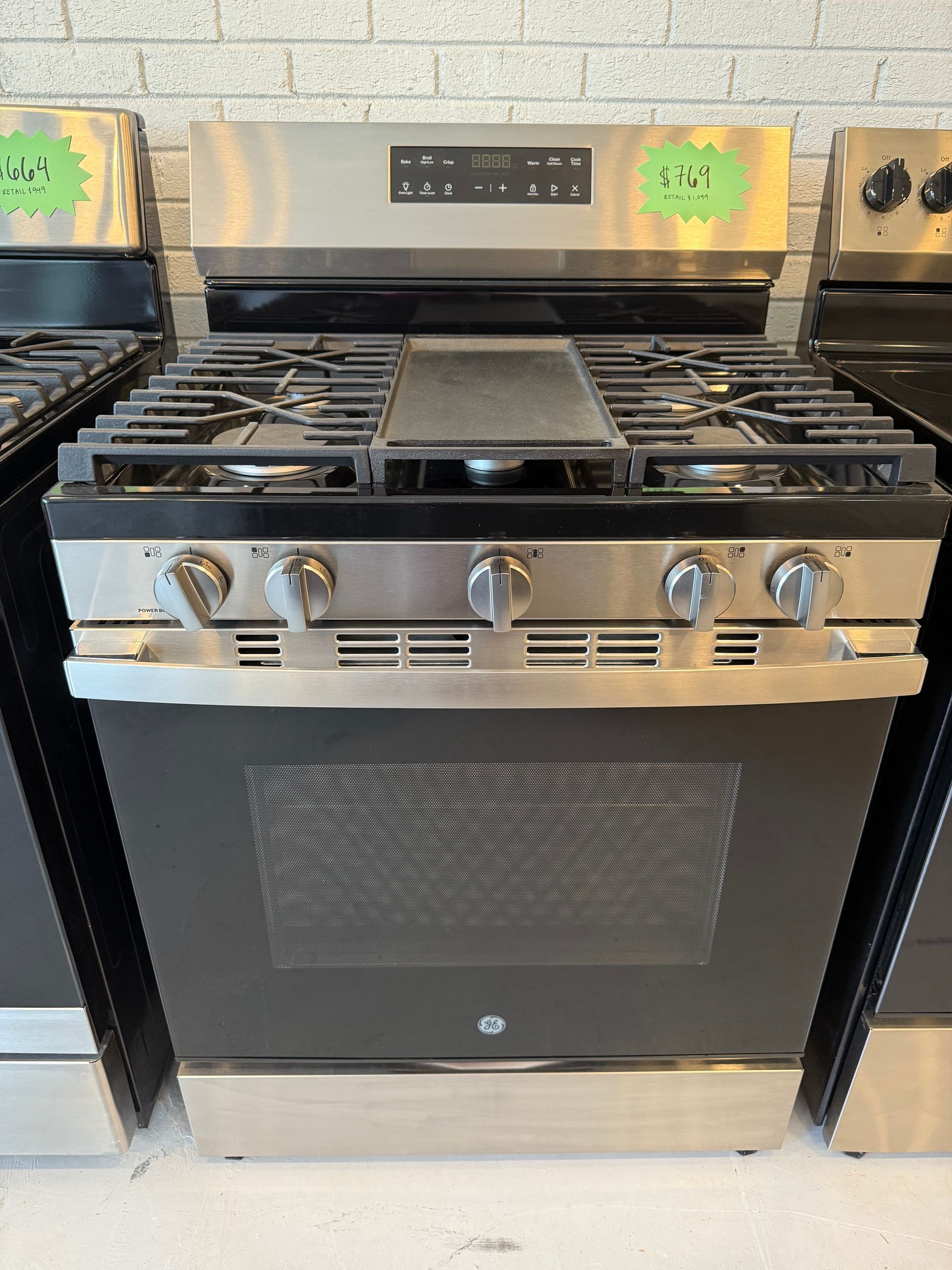 A stainless steel stove top oven with a green tag on it.