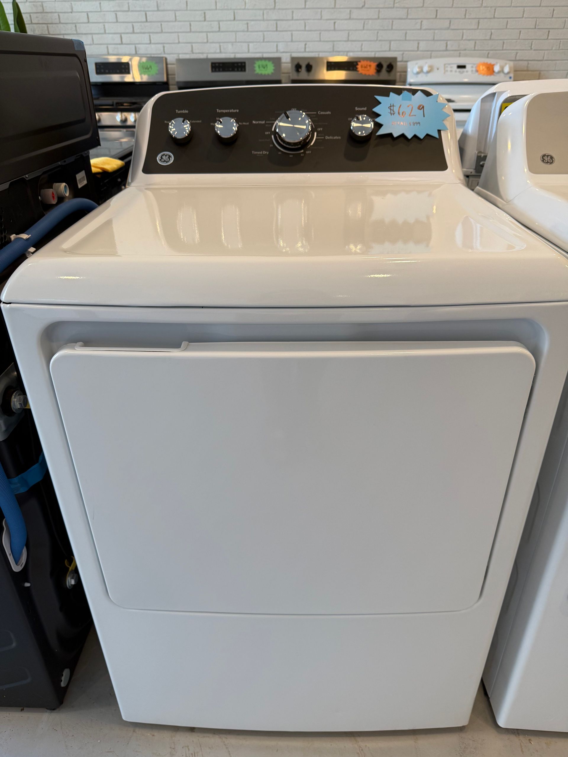 A white dryer is sitting on the floor in a store.