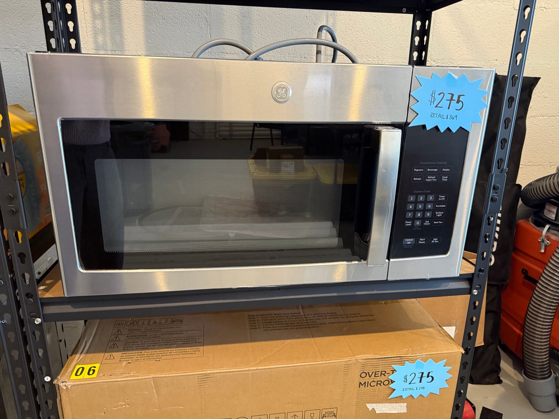 A stainless steel microwave oven is sitting on top of a shelf.