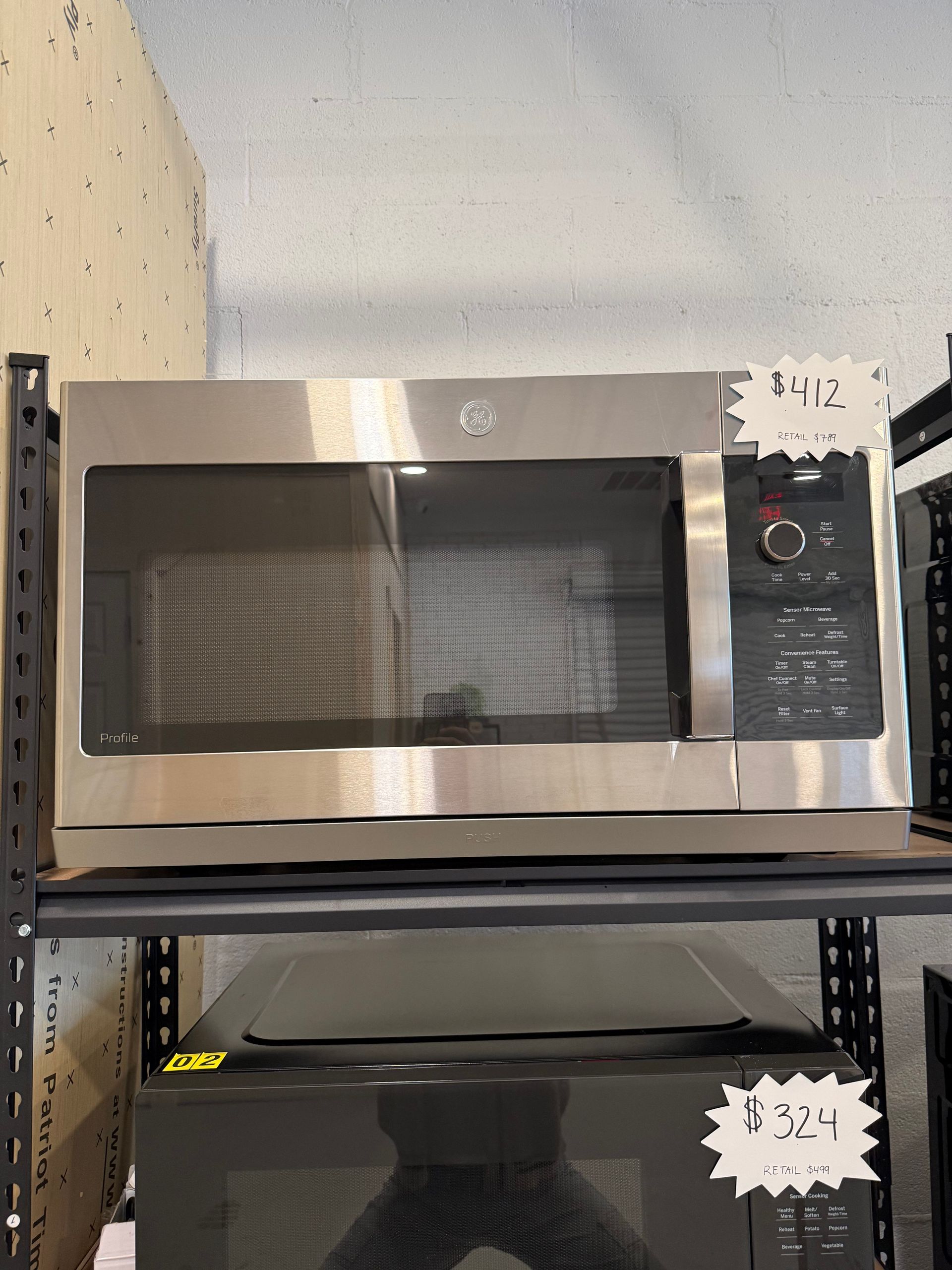A stainless steel microwave oven is sitting on top of a shelf