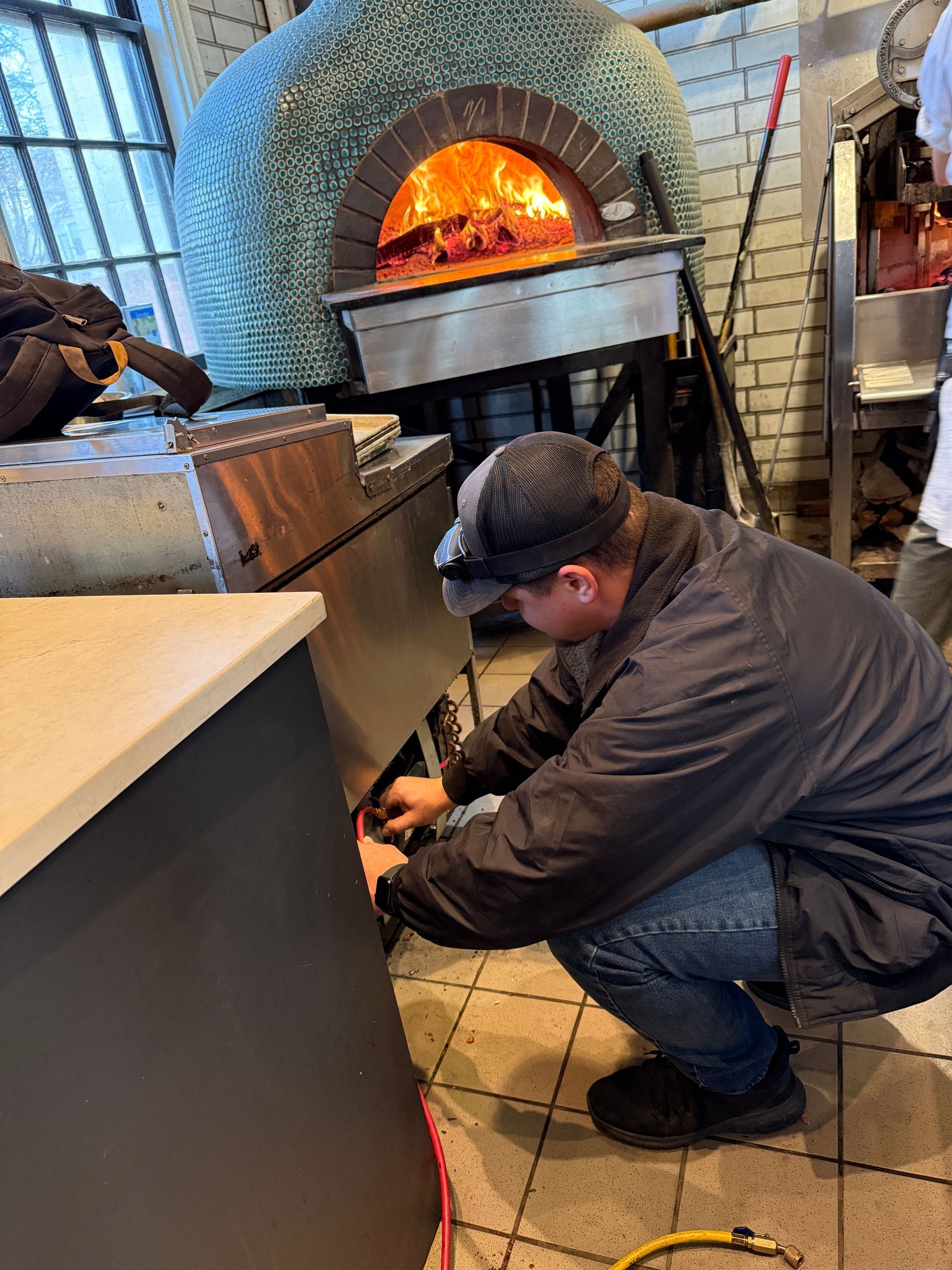 A man is working on a pizza oven in a kitchen.