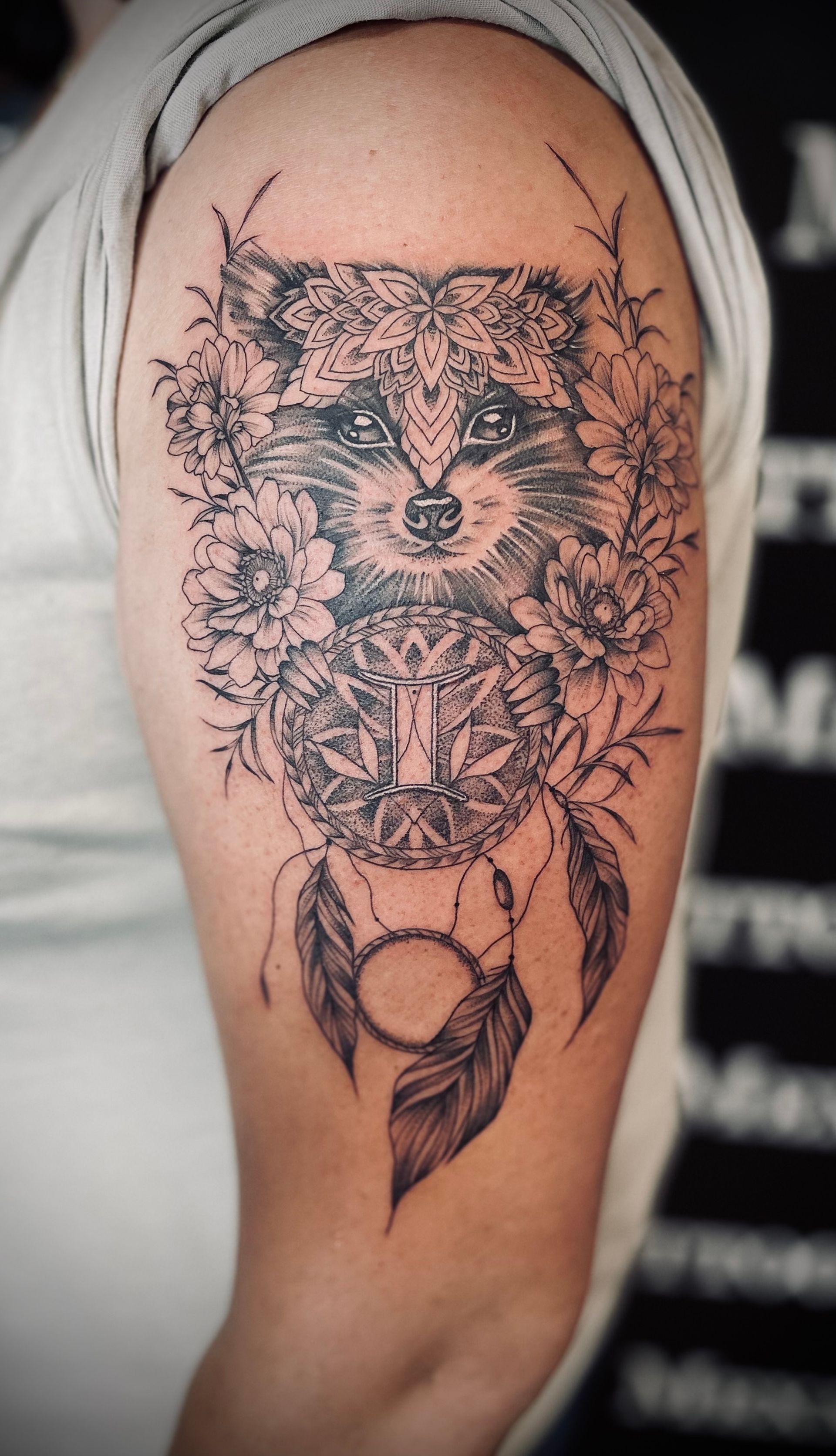 eine Frau hat ein Tattoo eines Waschbären und eines Traumfängers auf ihrem Arm .