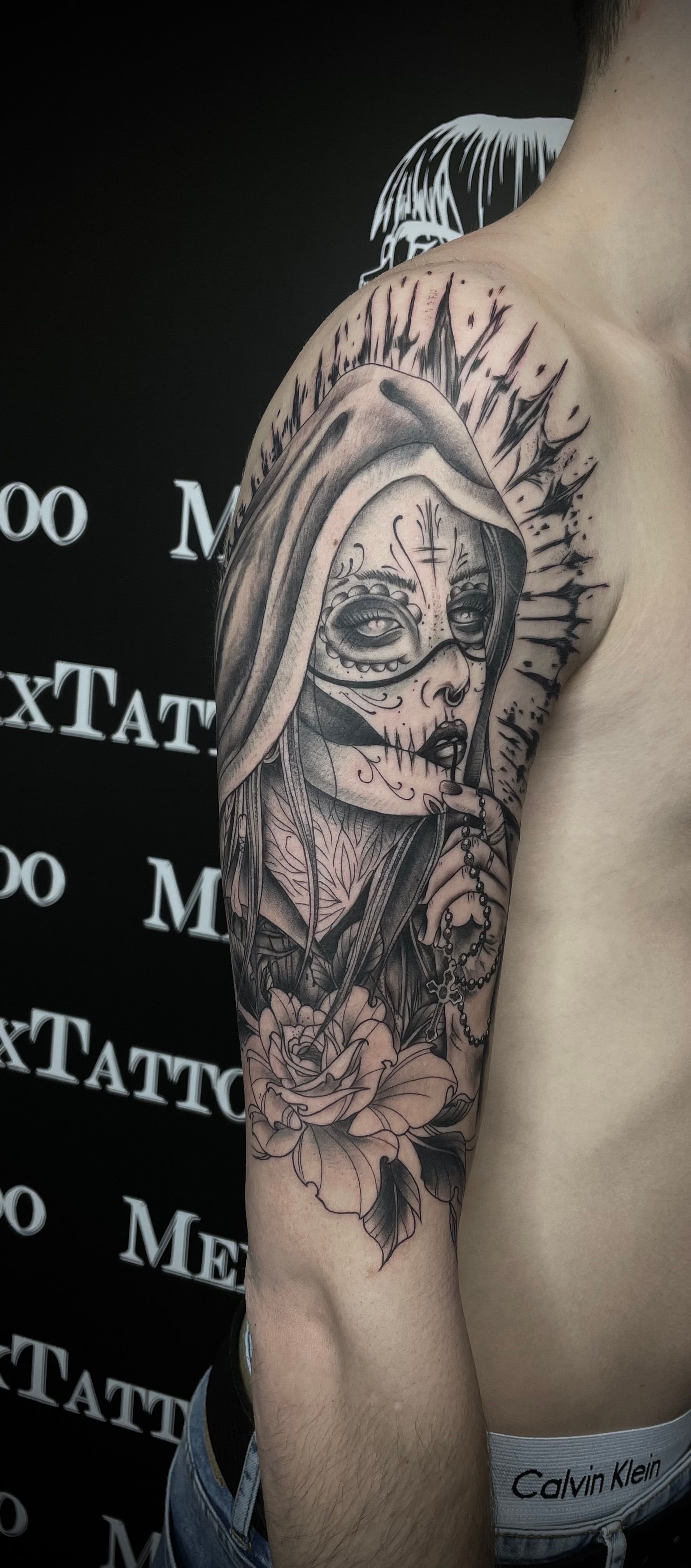 ein Mann ohne Hemd hat ein Schwarz-Weiß-Tattoo auf seinem Arm .