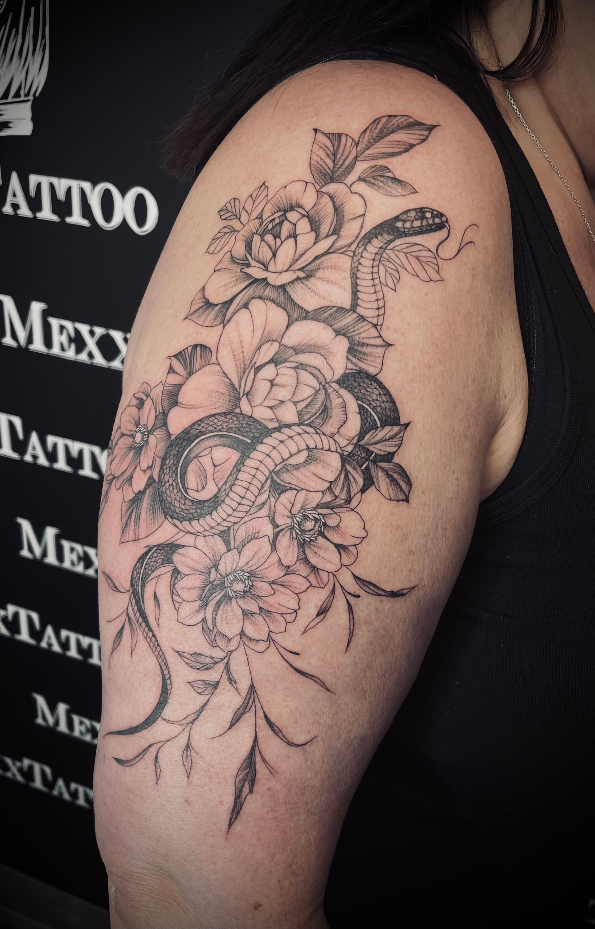eine Frau mit einem Blumen- und Schlangentattoo auf ihrem Arm