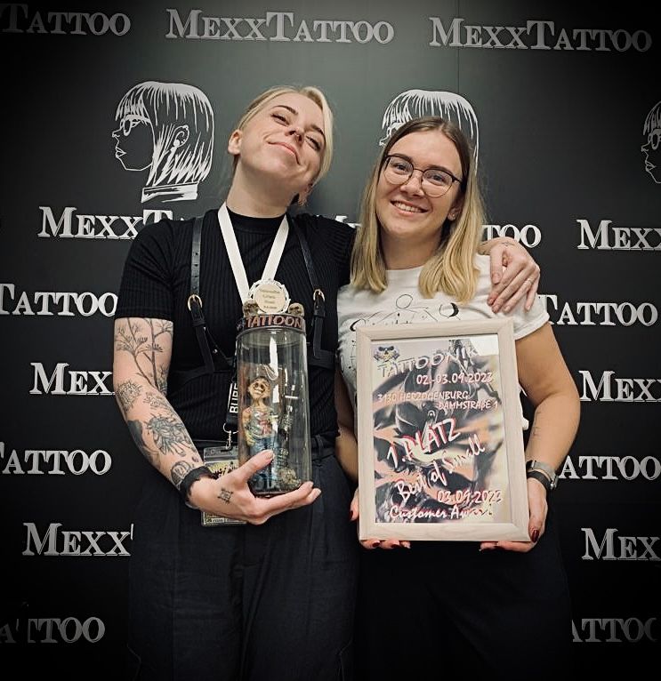 zwei Frauen stehen nebeneinander und halten eine Trophäe in der Hand .