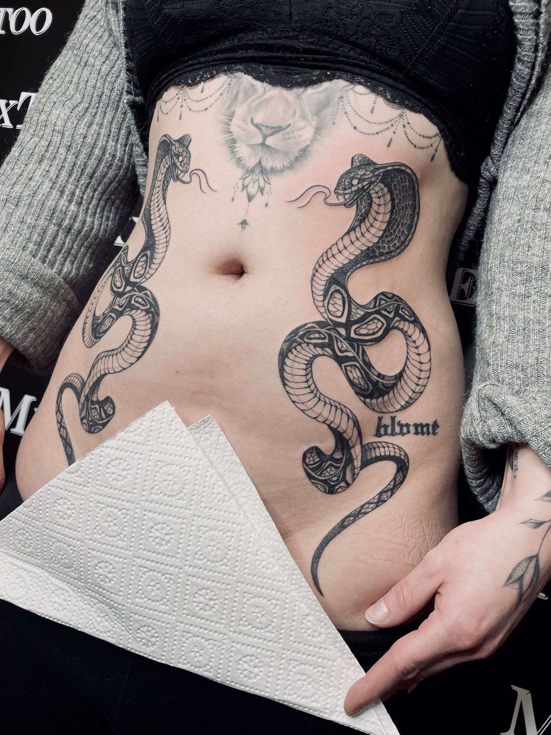 eine Frau mit einem Schlangentattoo auf ihrem Bauch