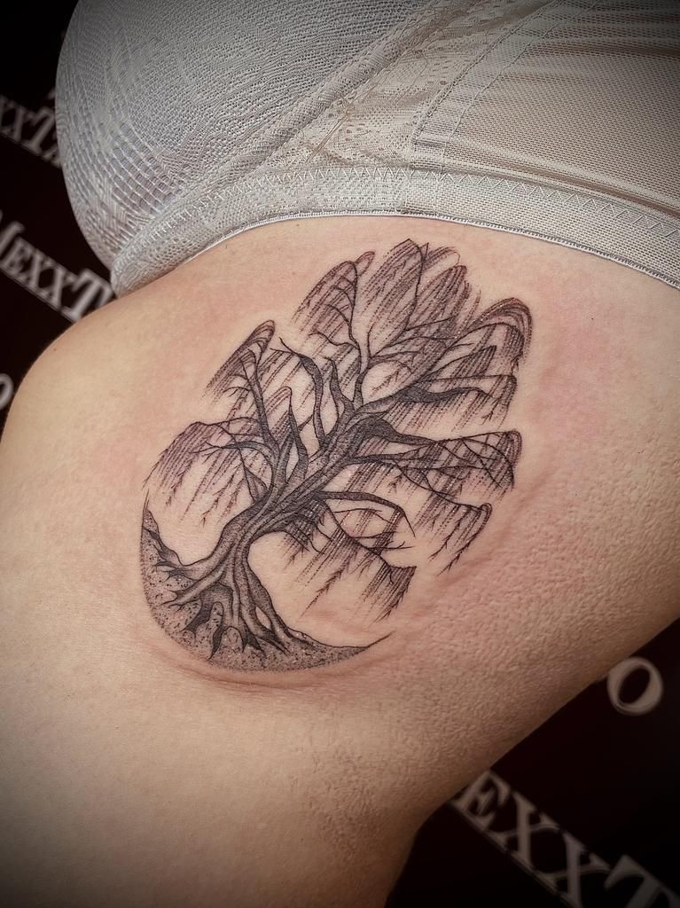 eine Frau mit einem Baumtattoo auf ihrem Oberschenkel