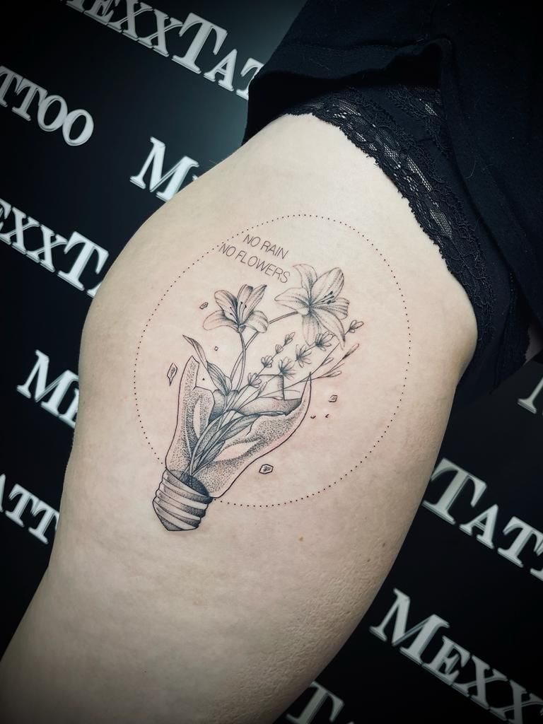 eine Frau hat ein Tattoo einer Glühbirne mit Blumen darauf .