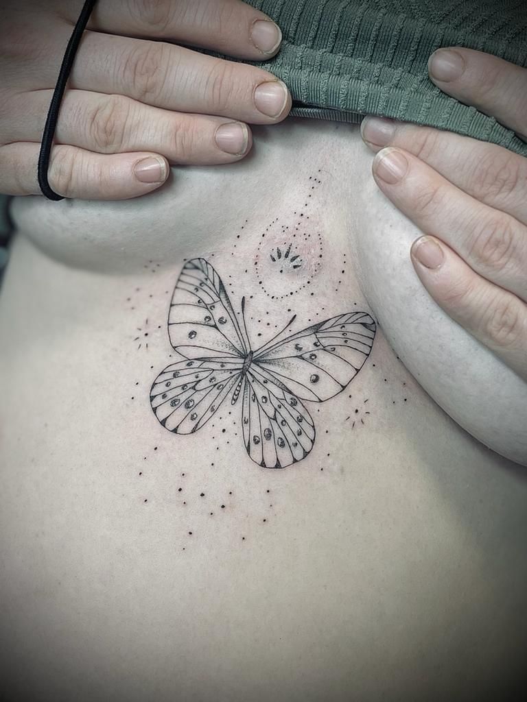 eine Frau mit einem Schmetterling-Tattoo auf ihrer Brust .