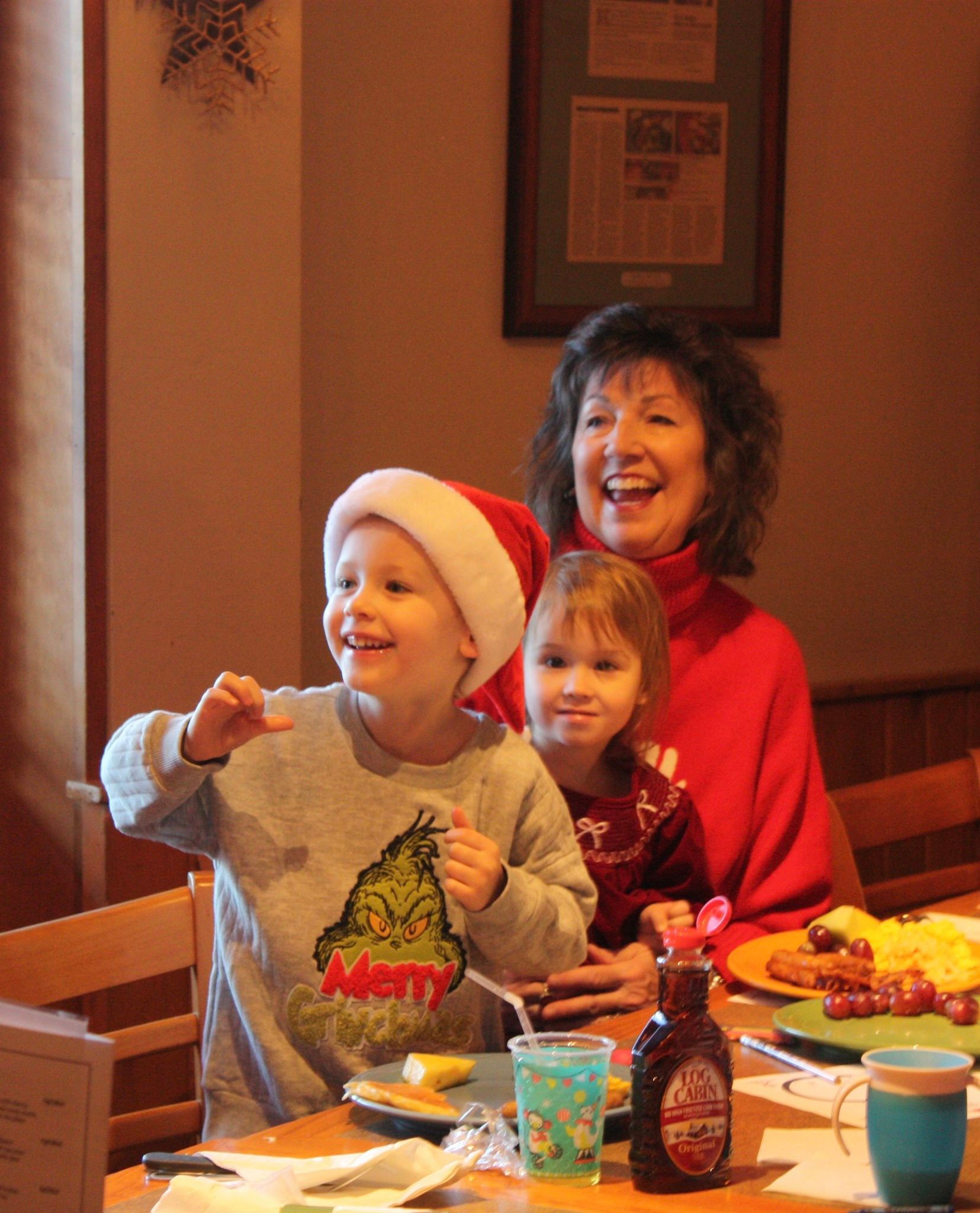 Woman with two children at a table, smiling. 
