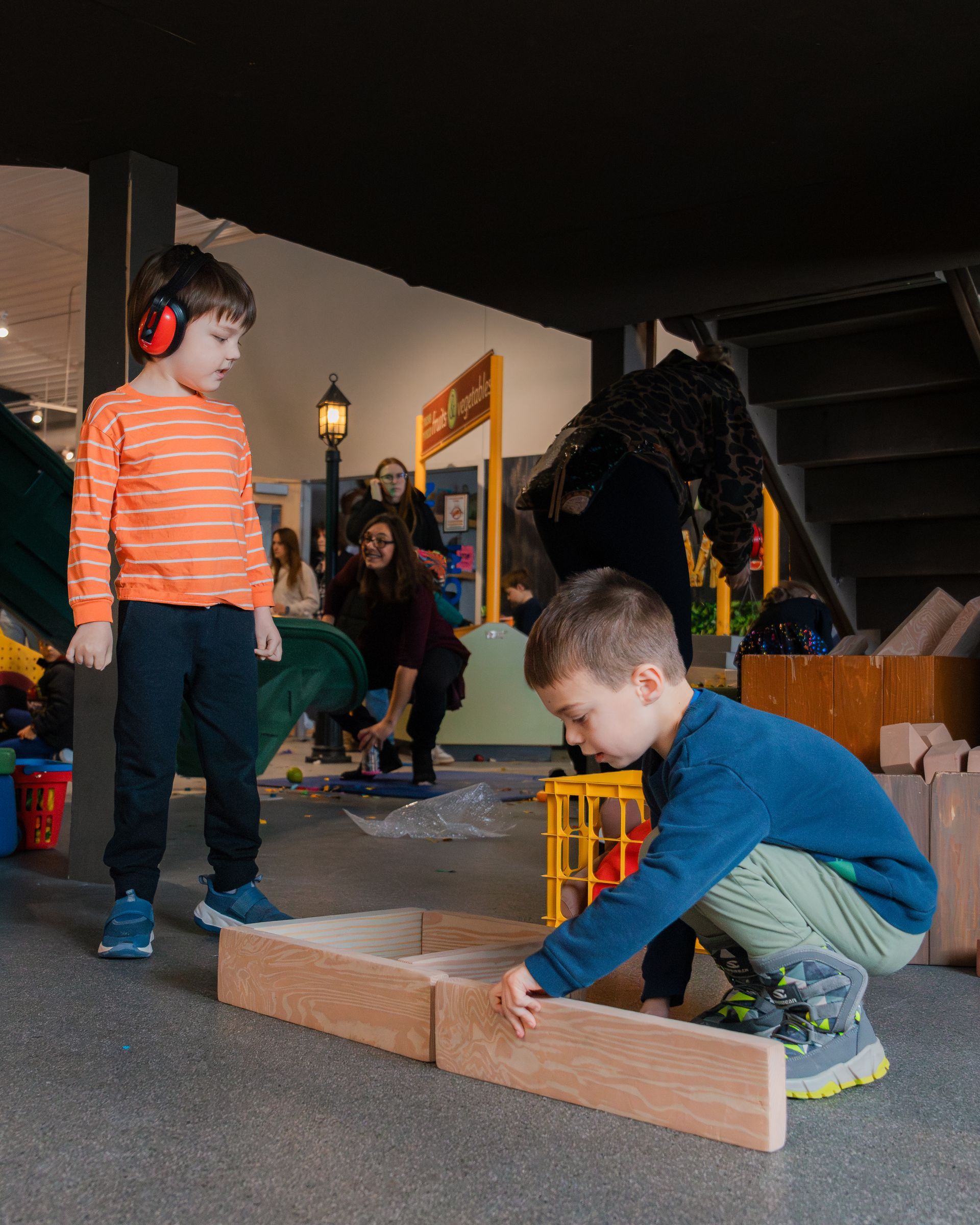 Children playing constructing a building. One child wears ear protection. 