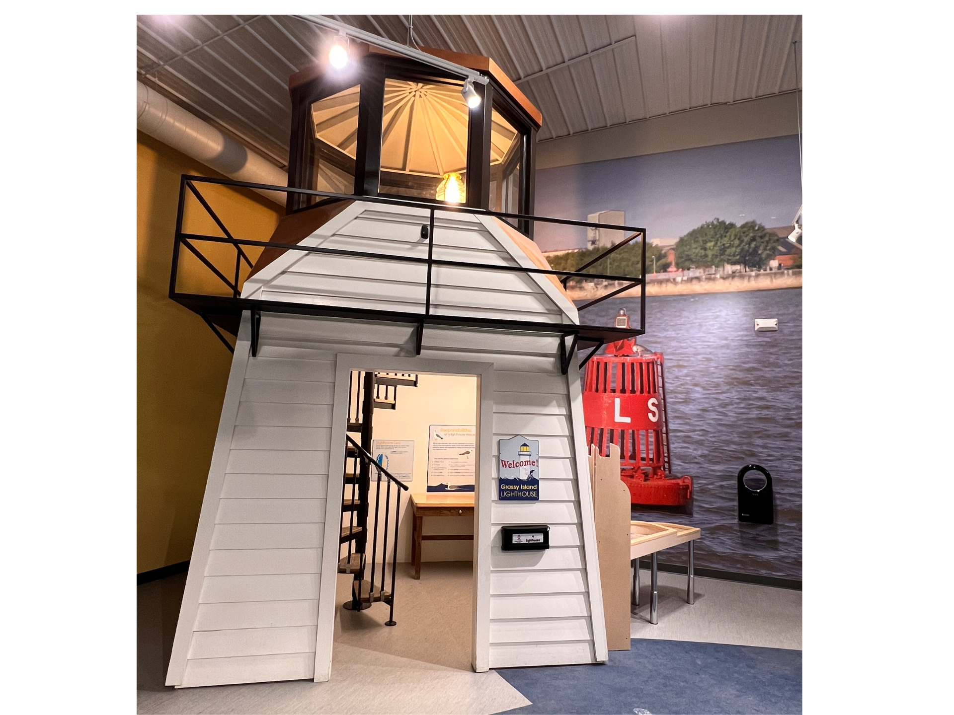 A lighthouse shaped playhouse with stairs and a balcony