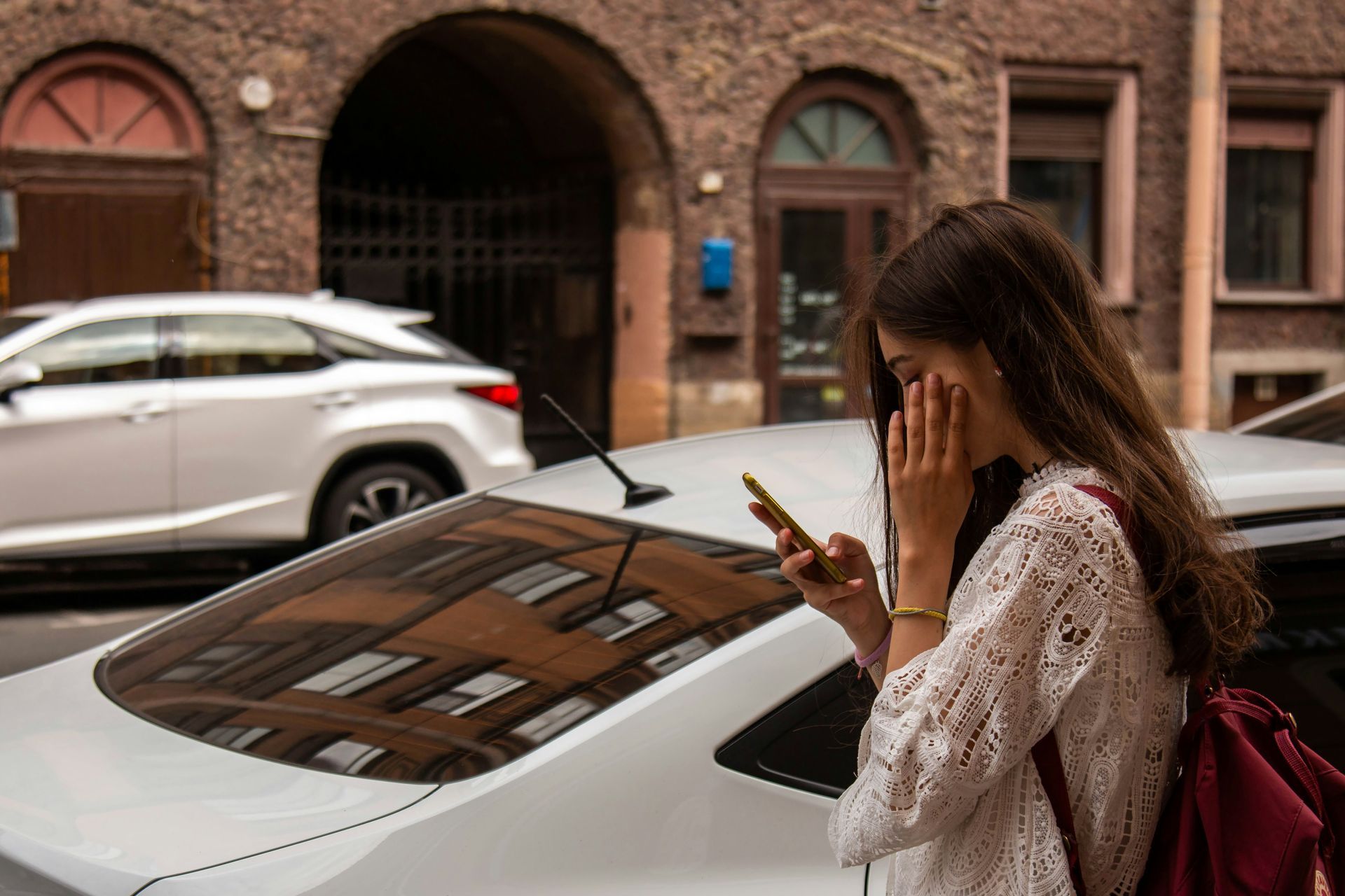 A woman is standing in a hallway looking at her cell phone.