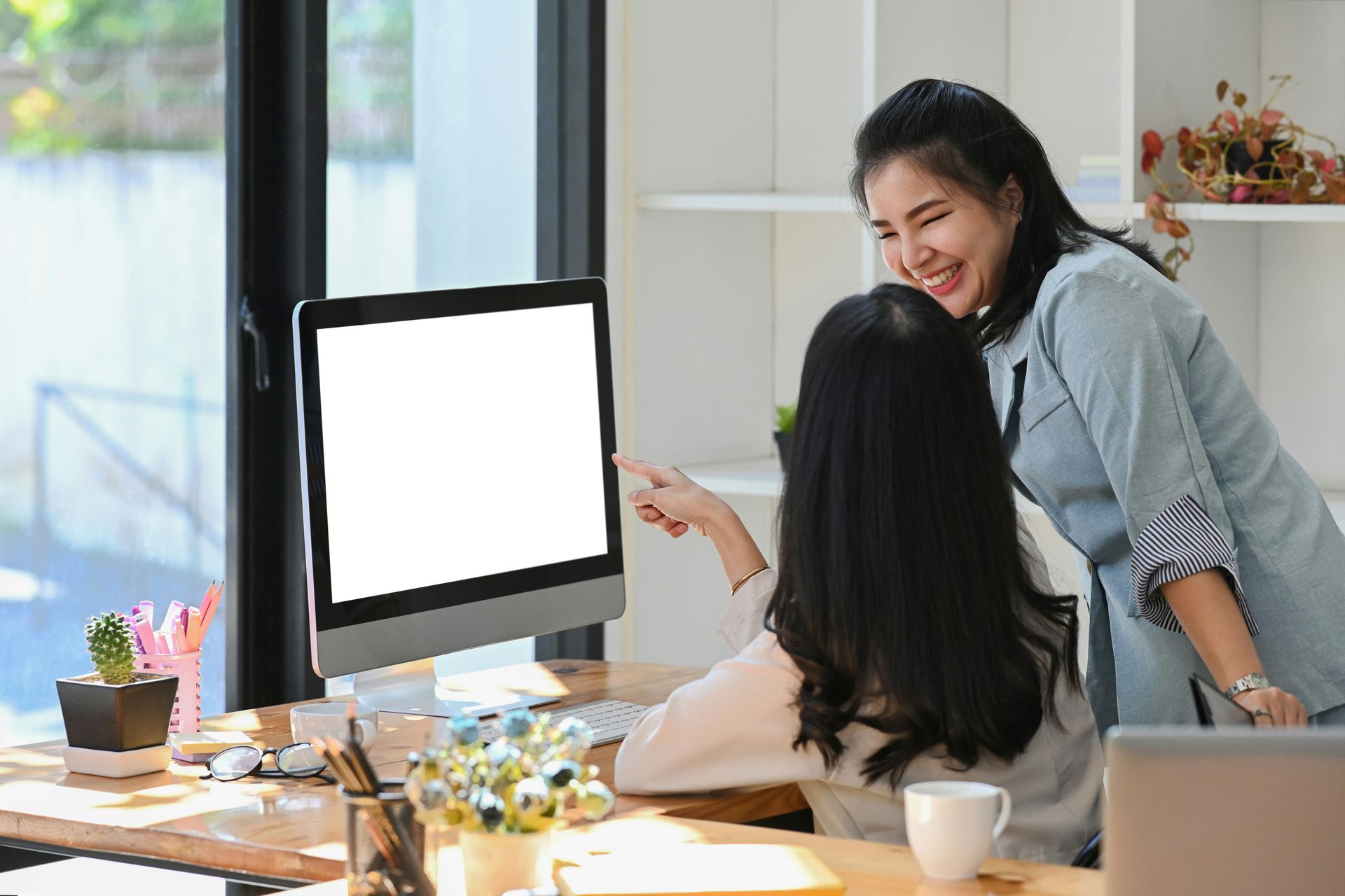 A man and a woman are looking at a laptop computer in a kitchen.