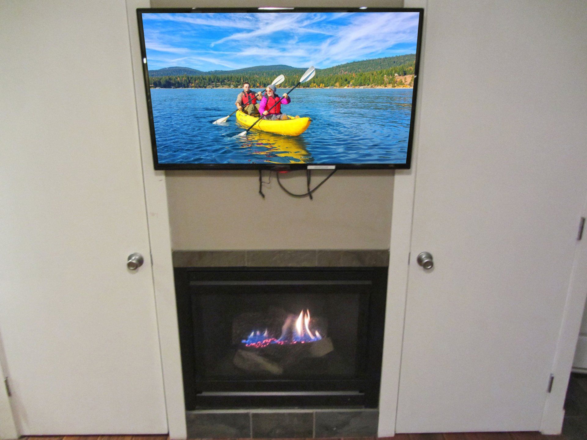 A flat screen tv is mounted above a fireplace.