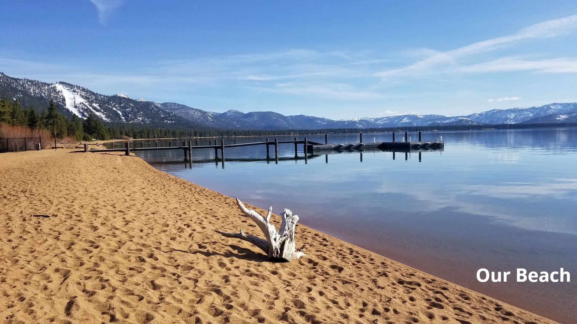A beach with a dock and mountains in the background