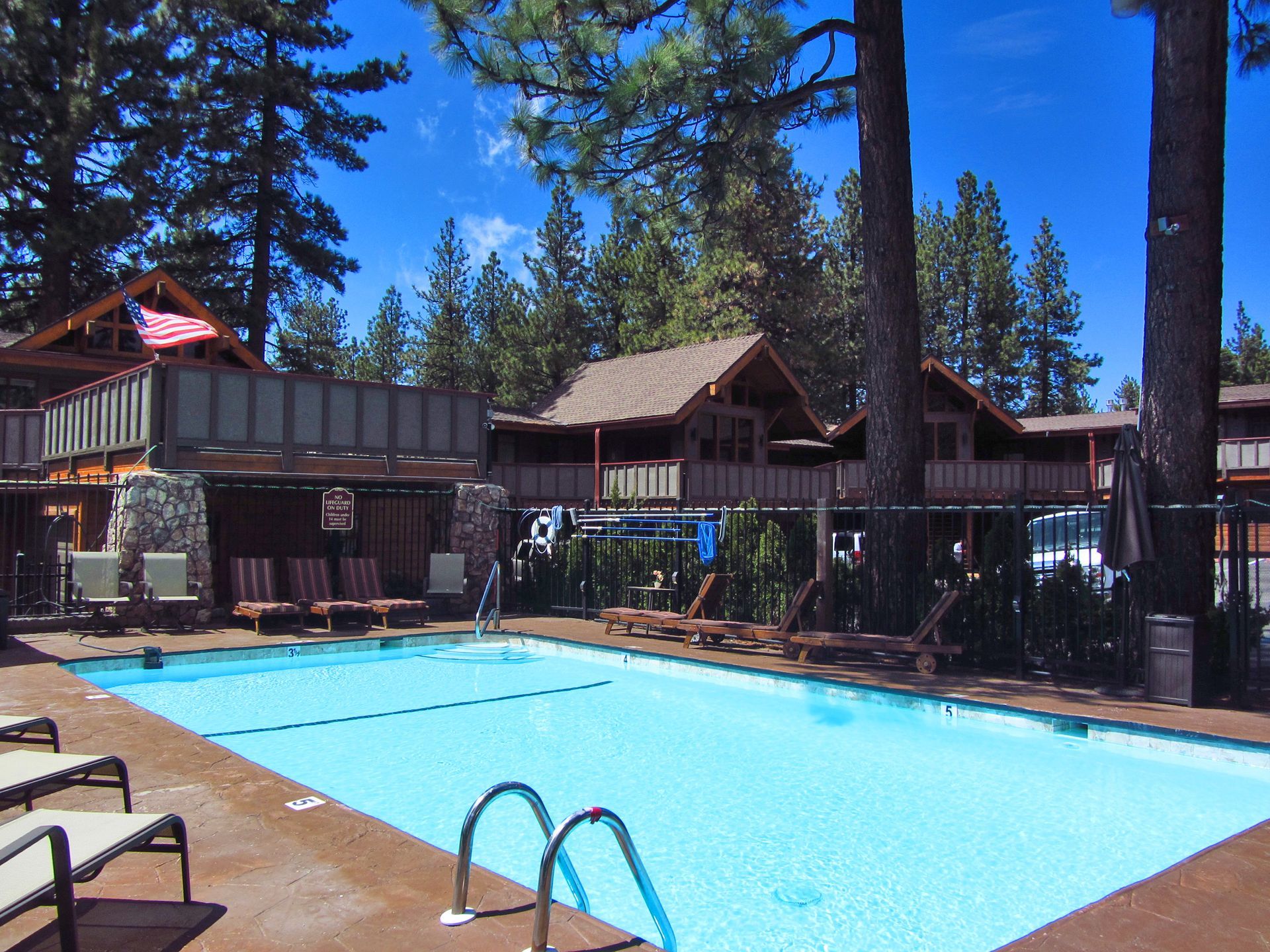 A large swimming pool is surrounded by chairs and trees