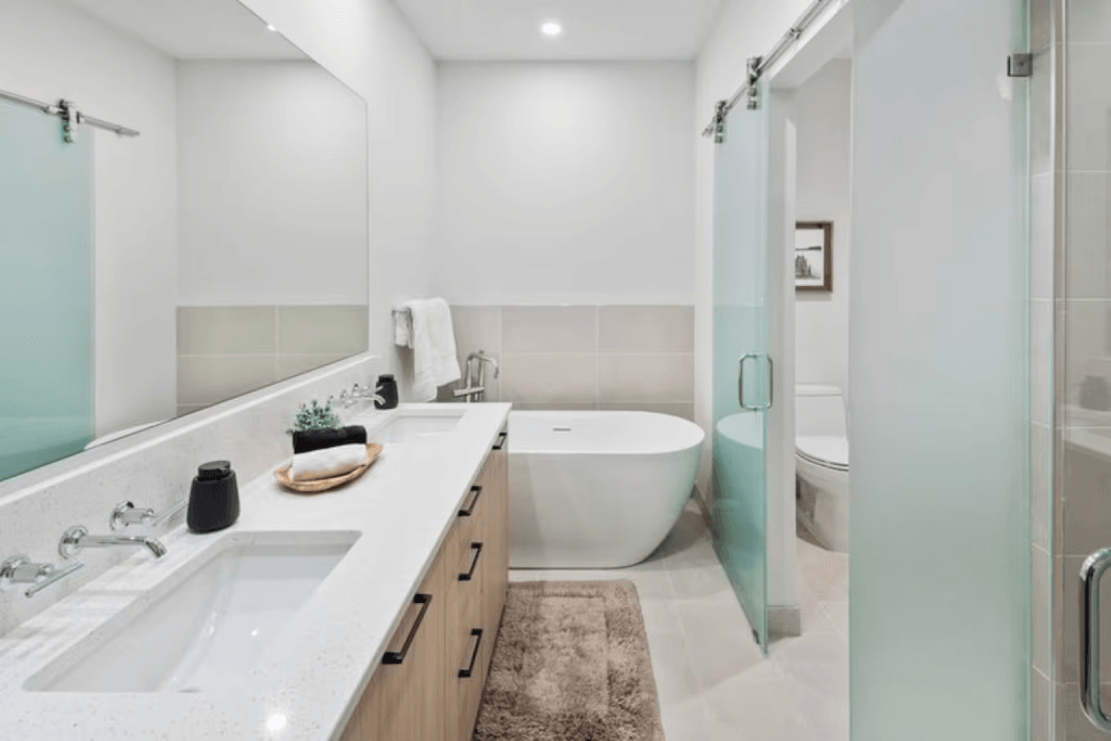 A bathroom with two sinks , a tub , a toilet and a mirror.