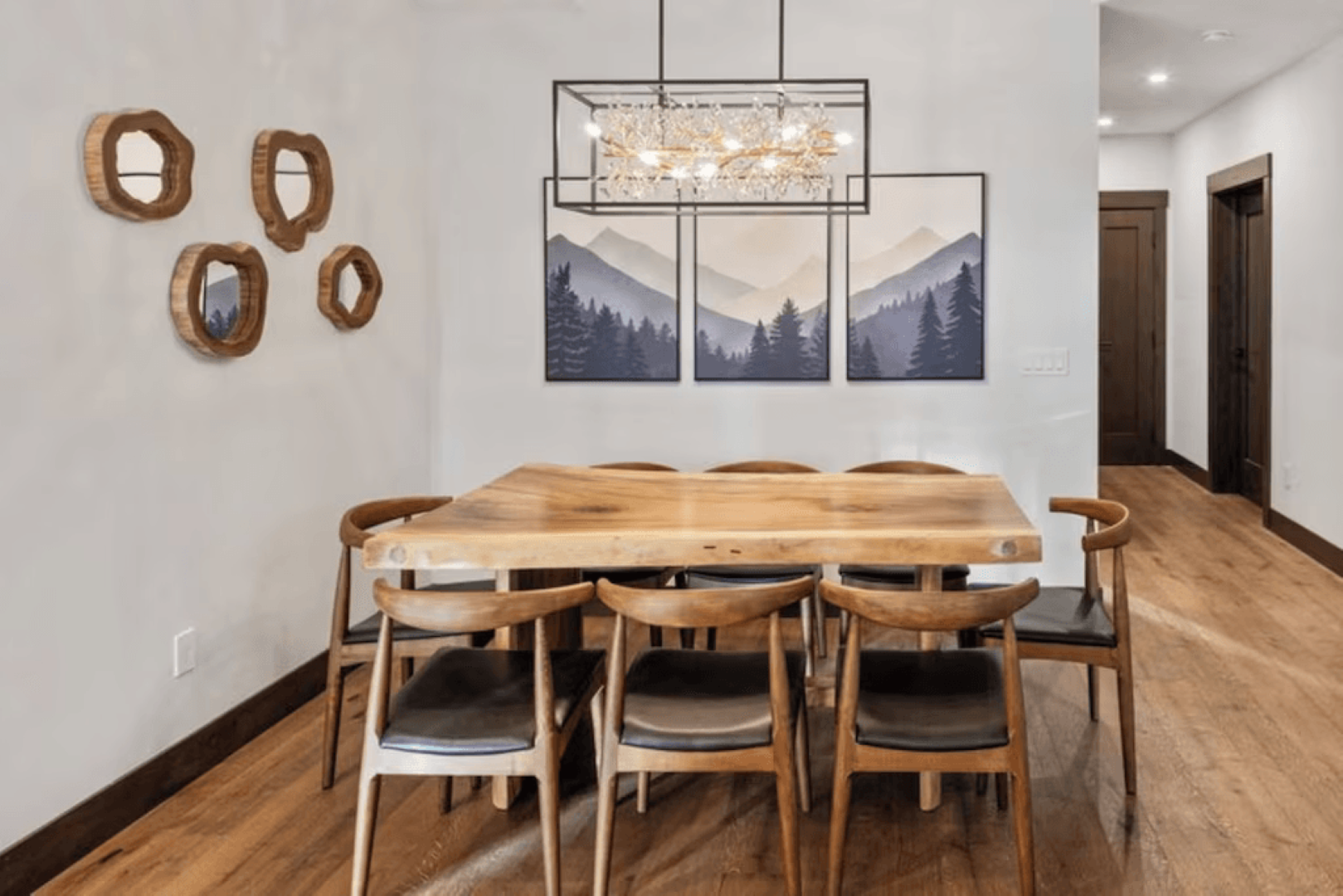 A dining room with a wooden table and chairs and a chandelier.