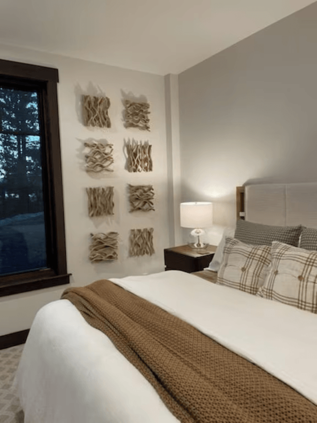 A bedroom with a bed , nightstand , lamp and window.