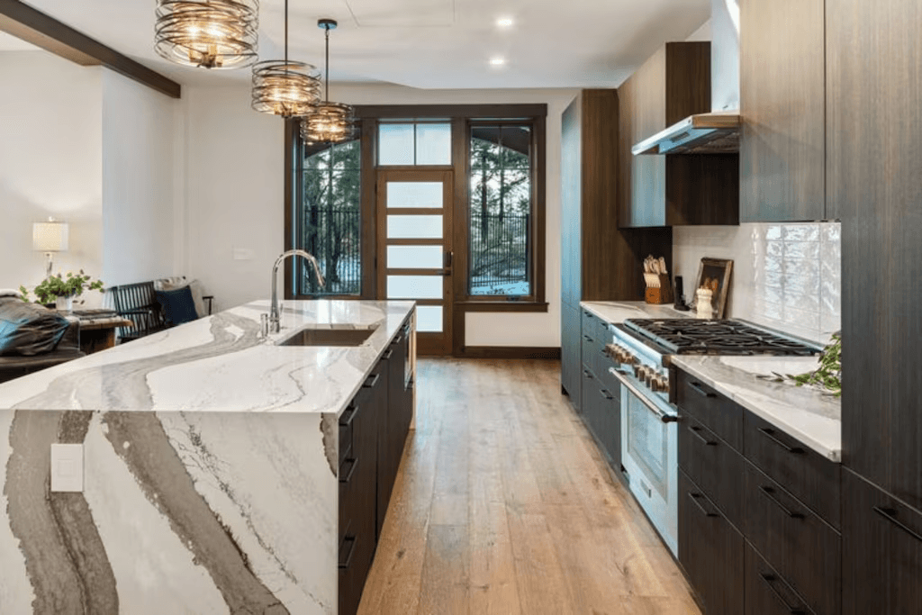 A kitchen with marble counter tops , wooden cabinets , stainless steel appliances and a large island.