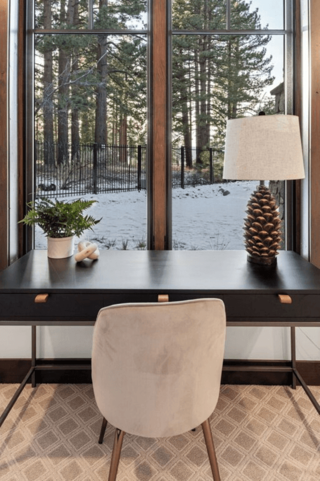 A desk with a lamp and a chair in front of a window.