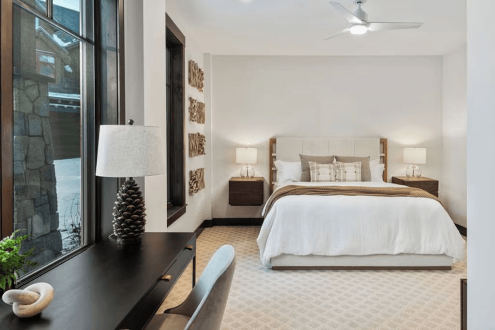 A bedroom with a large bed , desk , chair and ceiling fan.