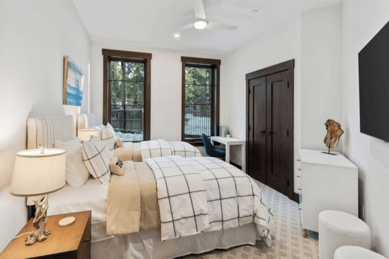 A bedroom with two beds , a desk and a television.