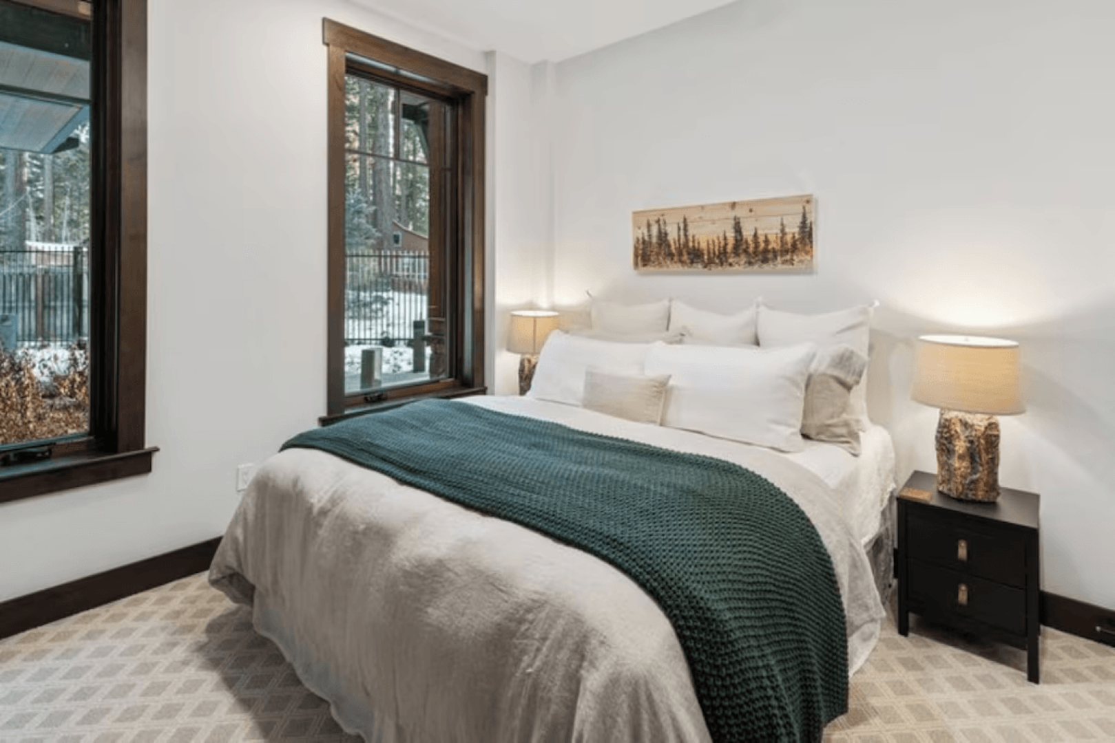 A bedroom with a bed , nightstand , lamps and a window.