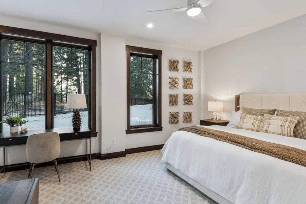 A bedroom with a large bed , a desk , a lamp , and a ceiling fan.