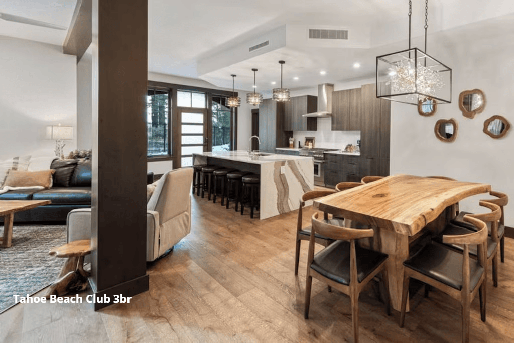 A living room with a wooden table and chairs and a kitchen.