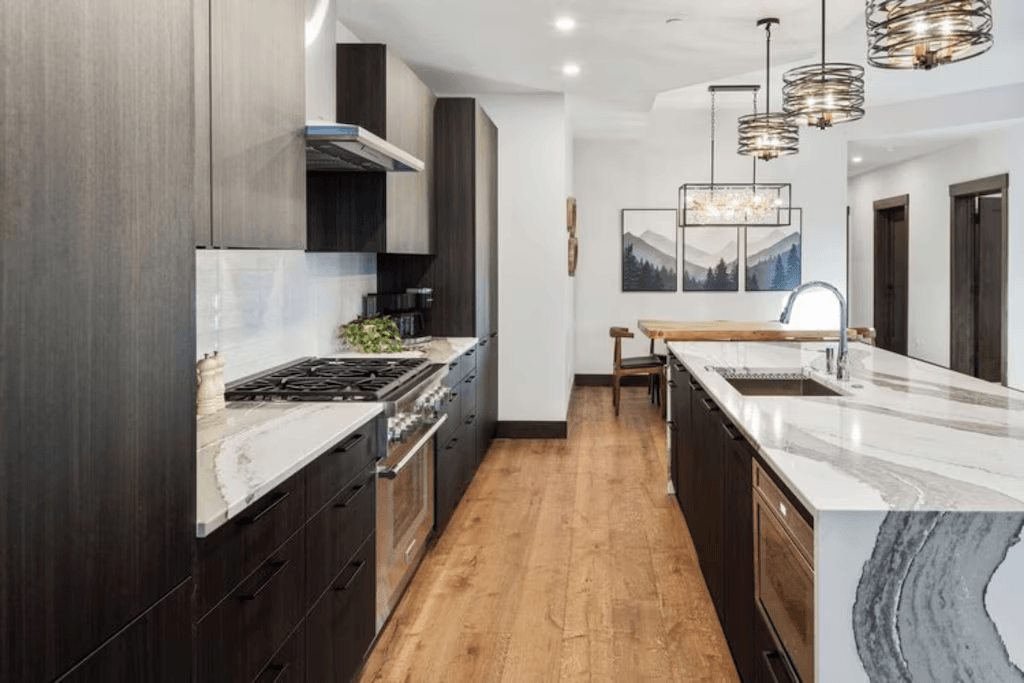 A kitchen with a stove , sink , and cabinets.