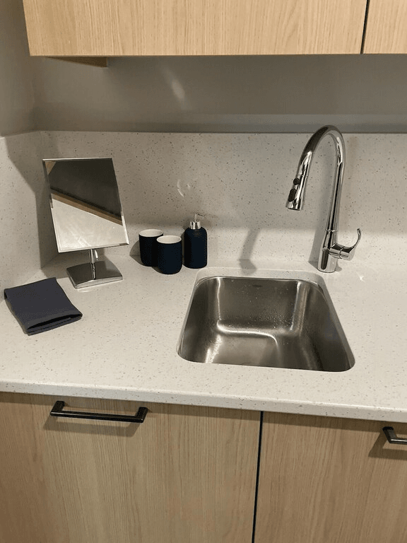 A kitchen counter with a sink and a mirror