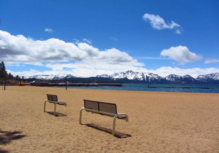 Two benches on a sandy beach with mountains in the background