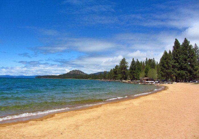 A sandy beach with a lake in the background