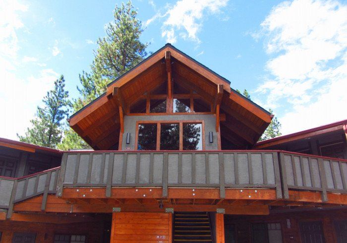 A large wooden house with a balcony and trees in the background