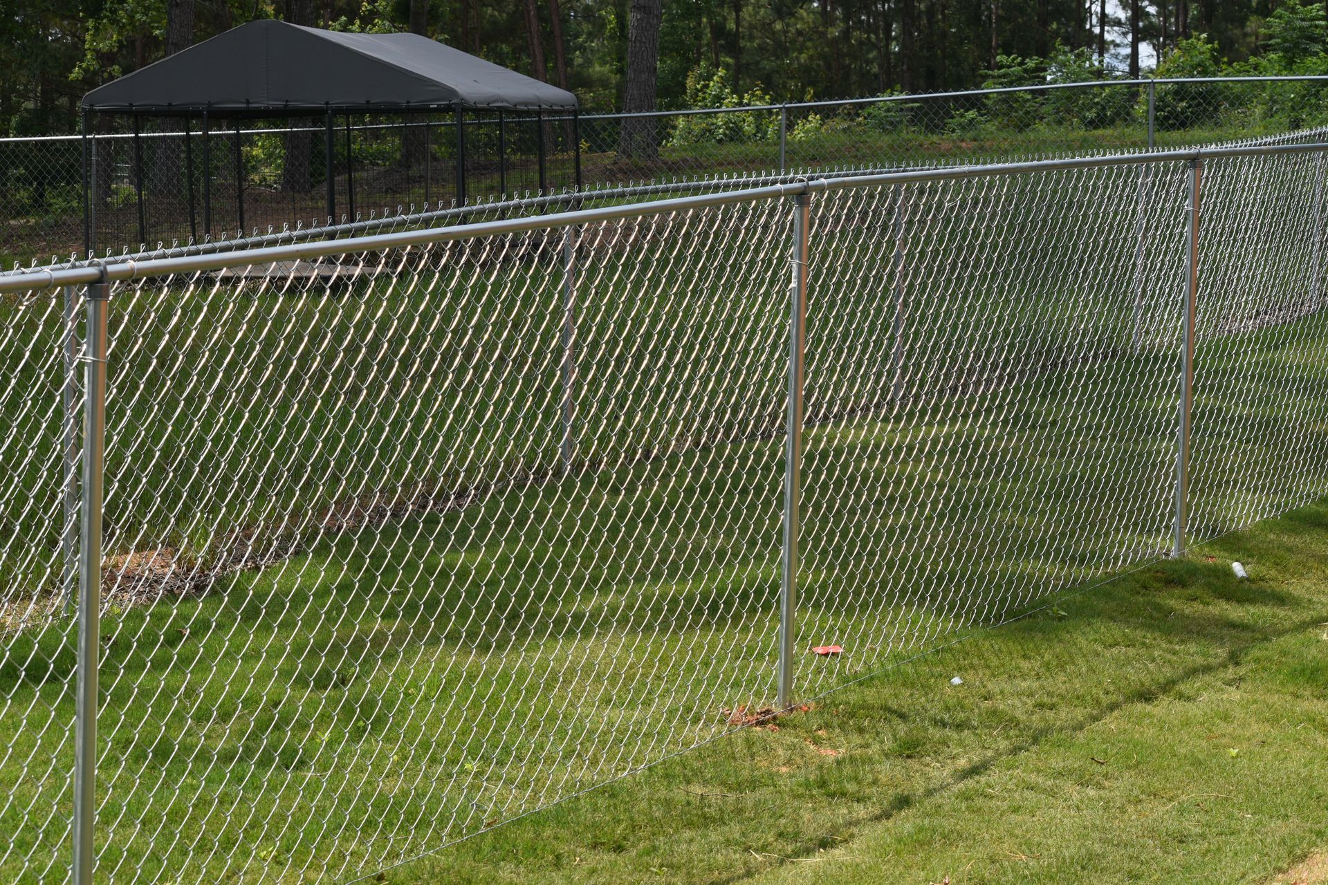 A chain link fence with barbed wire against a blue sky