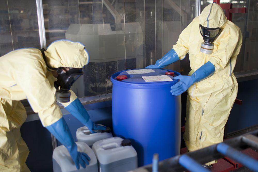 Two People in Protective Suits Are Working on A Blue Barrel — NQ Parks and Gardens in Cairns, QLD