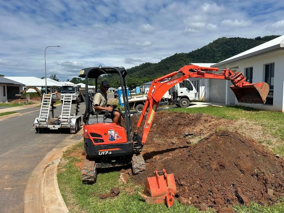 A Man Is Driving a Small Excavator on A Dirt Road — NQ Parks and Gardens in Cairns, QLD