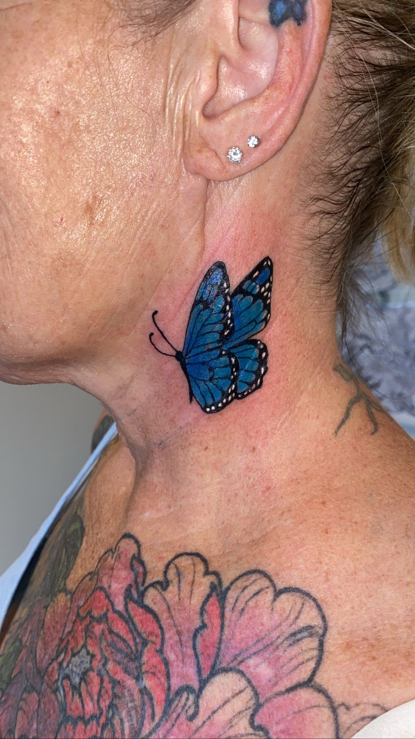 Blue butterfly tattoo on a person's neck; other tattoos on the body. — Pins and Needles Tattoo in Smithfield, QLD