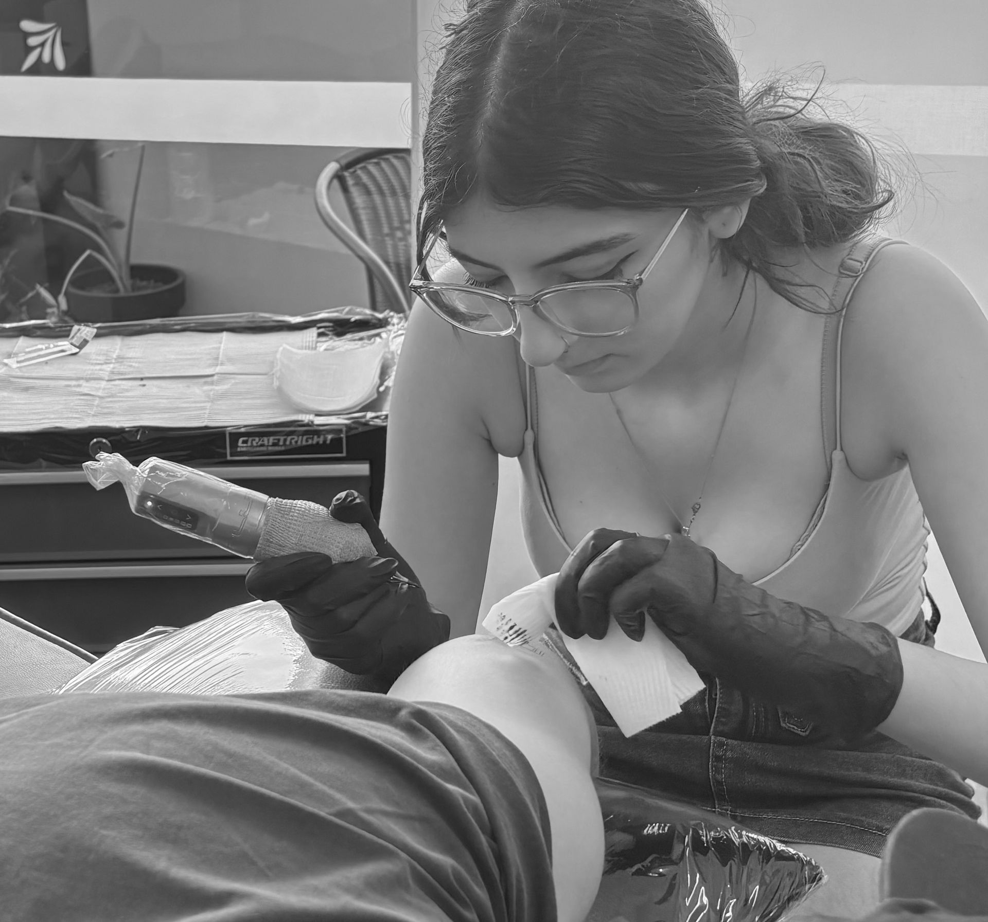 Tattoo Artist Leans Over Client, Applying Ink With a Pink Machine in a studio — Pins and Needles Tattoo in Trinity Beach, QLD