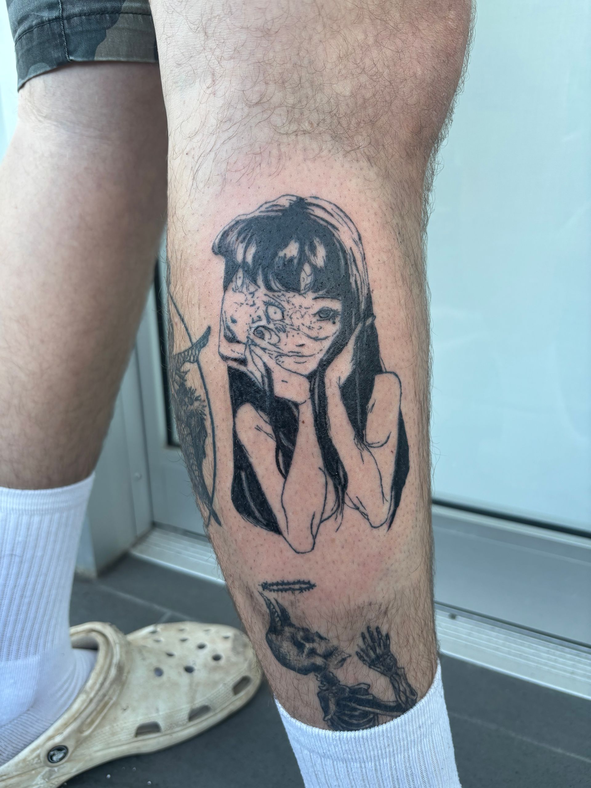 Tattoo of two birds in flight with a sunburst design on a person's shoulder, wearing a green tank top.