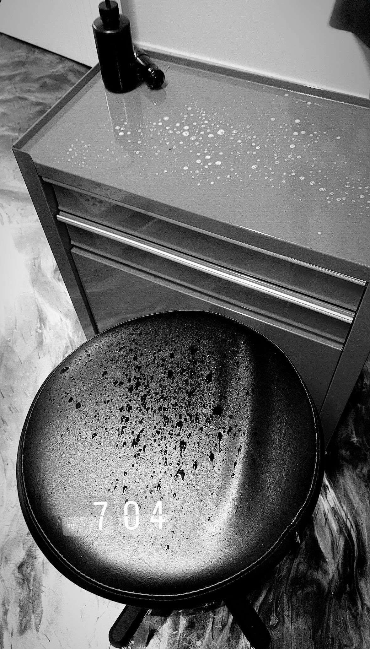 Stool and toolbox in a room. A dark stool sits in front of a metal cabinet with a bottle on top. — Pins and Needles Tattoo in Smithfield, QLD