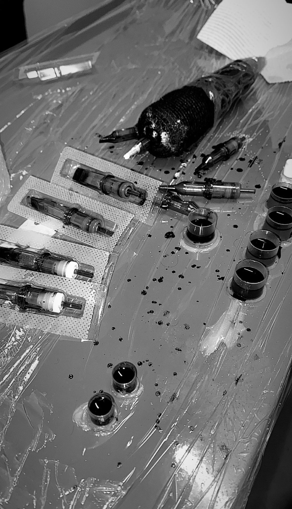 Tattoo equipment on a covered table: gun, needles, ink, and cups. — Pins and Needles Tattoo in Smithfield, QLD