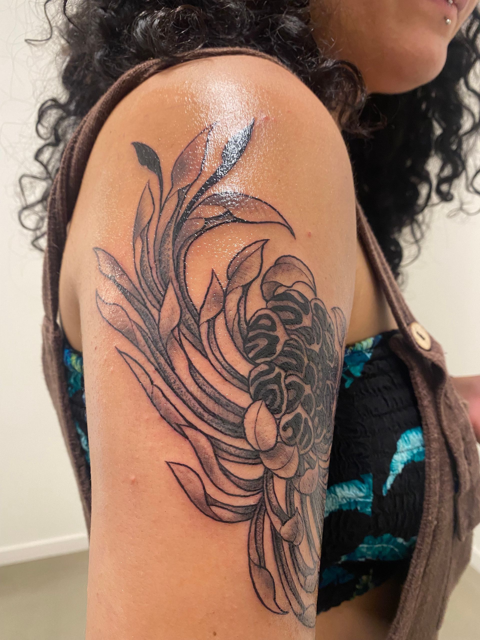 Tattoo of gray flower and leaves on a person's upper arm. — Pins and Needles Tattoo in Smithfield, QLD
