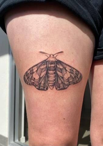 Black and white moth tattoo on a person's thigh. — Pins and Needles Tattoo in Smithfield, QLD