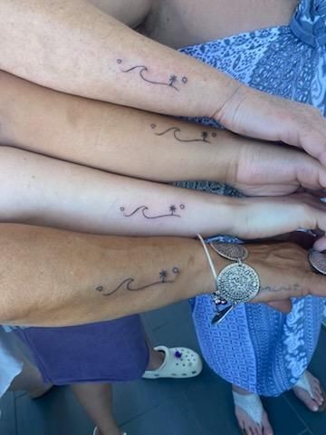 Four arms with matching wave and palm tree tattoos.