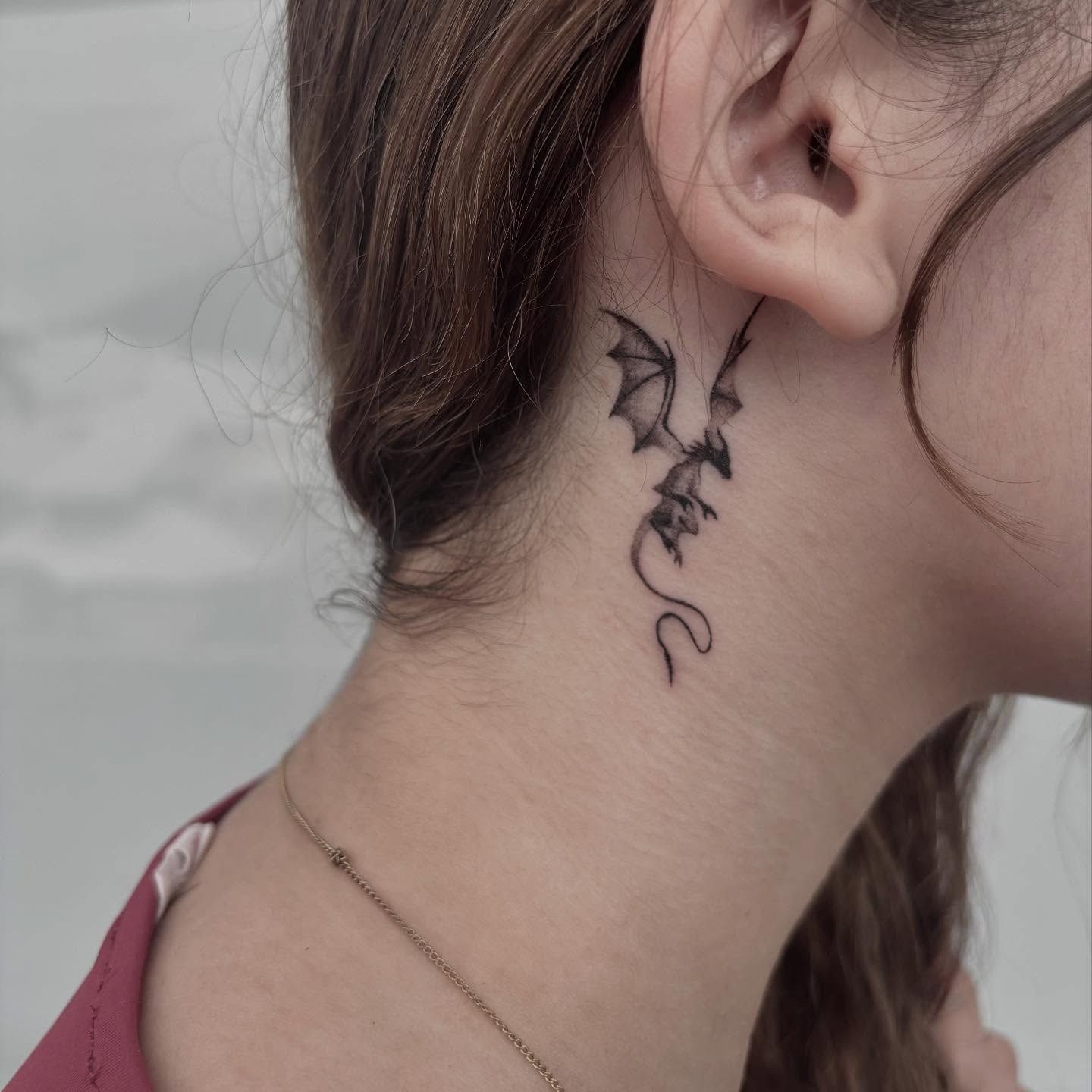 Tattoo of a Small Dragon With Outstretched Wings on the Back of a Neck — Pins and Needles Tattoo in Trinity Beach, QLD