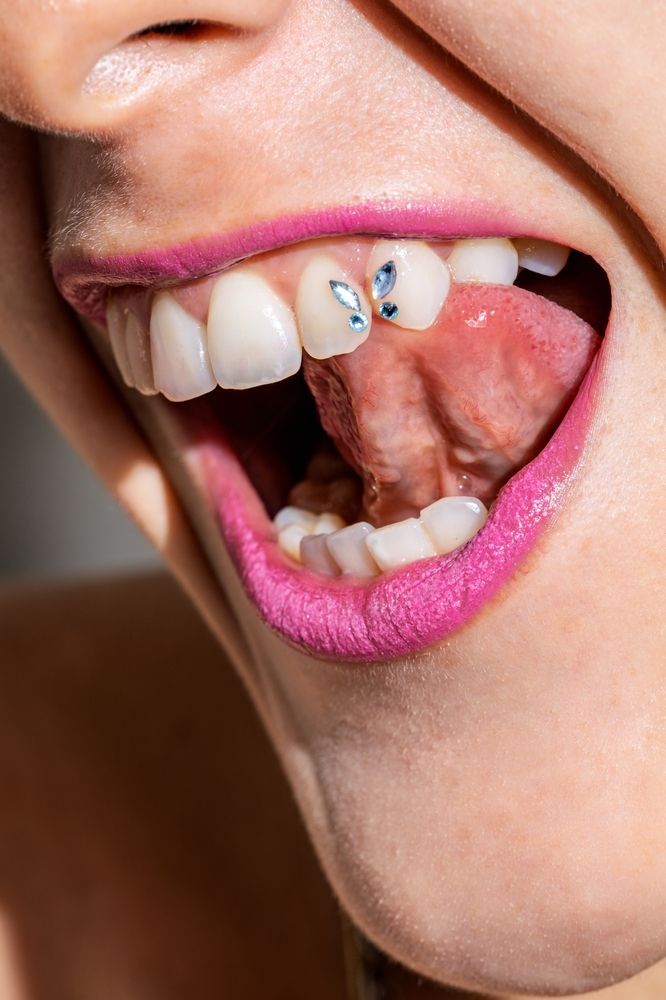 Close-up of a Person Smiling, Showing Teeth With a Jewel, Tongue Visible — Pins and Needles Tattoo in Smithfield, QLD
