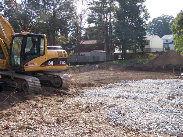 A yellow cat excavator is working in a gravel area